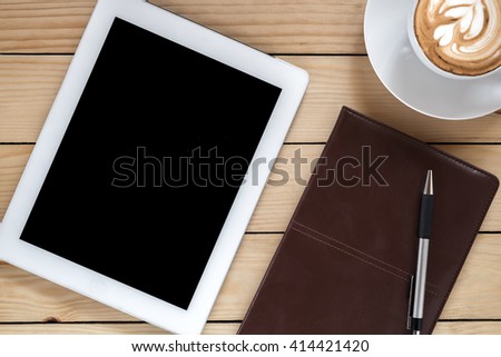 Office stuff with leather notebook,blank screen tablet, coffee cup and pen.Flat lay photo.Top view with copy space.Flat lay images.Office gadget on wooden table.