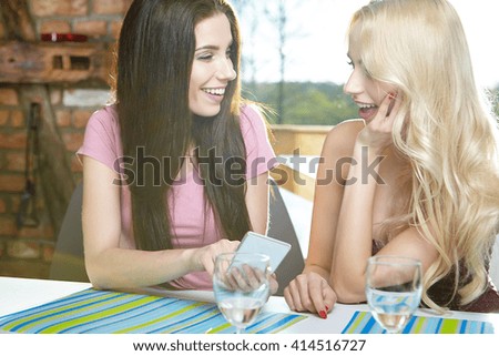 Two girls taking pictures on the phone at home