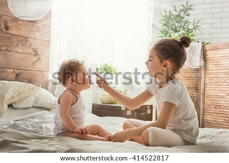 two cute child baby girls playing and having fun on the bed. loving sisters hug Royalty-Free Stock Photo #414522817