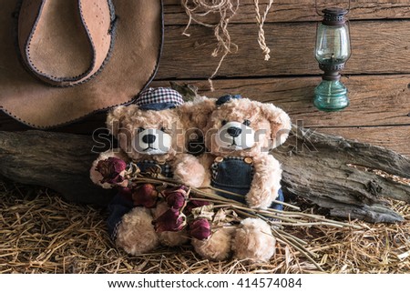 Two teddy bears holding dry roses and take a photo in barn studio, love and friendship concept
