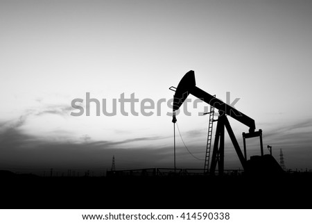 Sunset and silhouette of crude oil pump in the oilfield - black and white