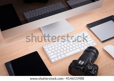 DSLR digital camera with tablet and computer PC on wooden desk table