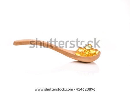Fish oil capsules in a wood spoon on white background