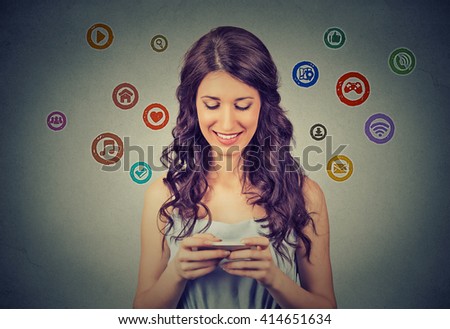 communication technology mobile phone high tech concept. Happy woman using texting on smartphone social media application icons flying out of cellphone isolated grey wall background. 4g data plan