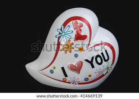 ceramic piggy bank in heart shaped isolated on black background.