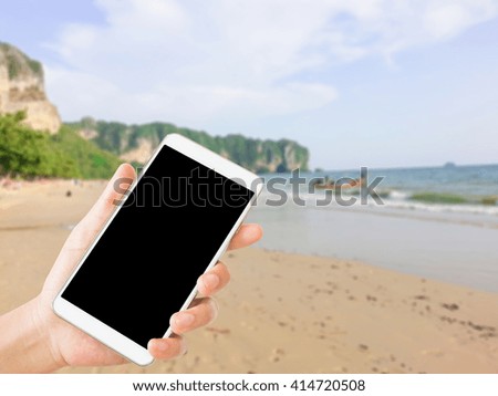 woman use mobile phone and blurred image of beach view in thailand