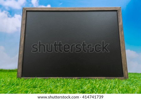 Blank black board on grass field