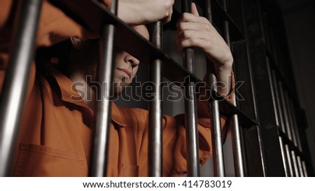 Man in jail behind bars - Caucasian young gang member Royalty-Free Stock Photo #414783019