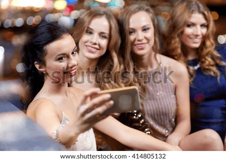 celebration, friends, bachelorette party, technology and holidays concept - happy women with smartphone taking selfie at night club