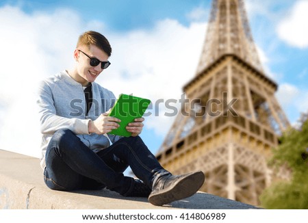 technology, travel, tourism and people concept - smiling young man or teenage boy with tablet pc computers over paris eiffel tower background