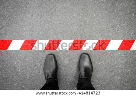 black shoes standing at the red-white line. Do not cross the line. It's prohibited and not allowed. It's limited. It's the end. Royalty-Free Stock Photo #414814723