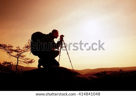 Amateur photographer takes photos with mirror camera on neck.  Dreamy foggy landscape, spring orange pink misty sunrise in a beautiful valley below