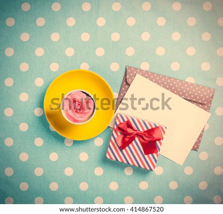 Cup of coffee and envelope with gift boxes on blue polka dot background 