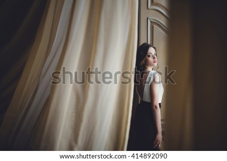 frail woman standing on the background of beautiful wall