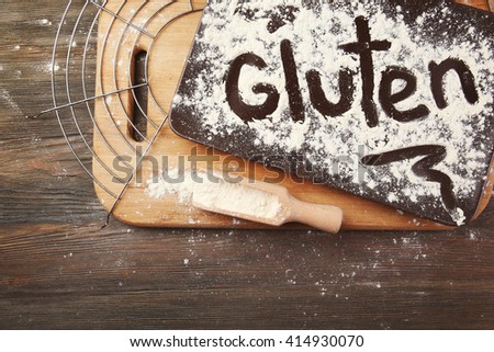 Gluten word written with flour on a tray over wooden table