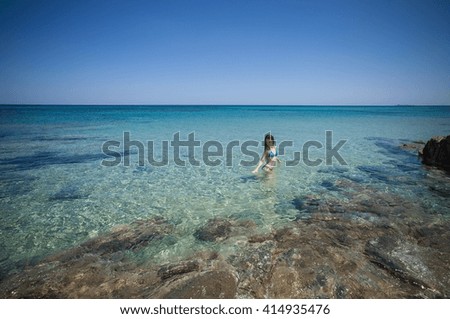 Young woman wearing bikini wading in sea, Cagliari, Sardinia, Italy