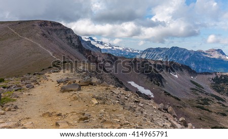 Rocky slopes in the mountains. Amazing view at the peaks which rose against the cloud sky. Path on the tops of mountains. BURROUGHS MOUNTAIN TRAIL, Sunrise Area, Mount Rainier National Park