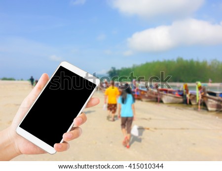 woman use mobile phone and blurred image of the beach in Krabi Thailand