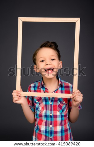 Portrait of happy laughing little boy with wooden frame