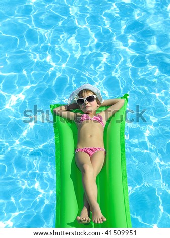  girl in the swimming pool in hat and sun glasses
