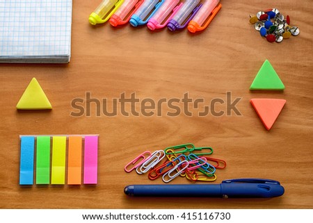 Business accessories and colorful office supplies (notebooks, pens, markers, crayons, paints, paper clips, rulers, stickers, eraser) on wooden table. With soft focus.