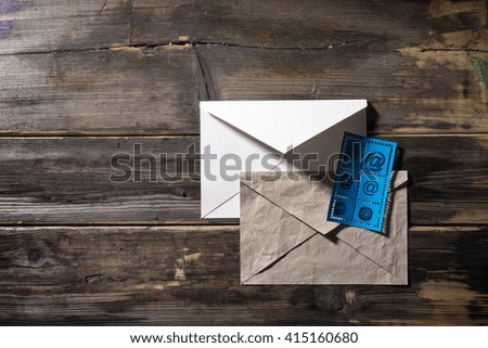 Old envelope and stamp with e-mail sign lie on a vintage table.