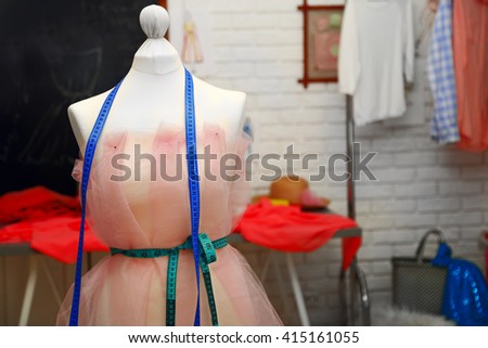 Tailor dummy with measuring tapes in fashion studio