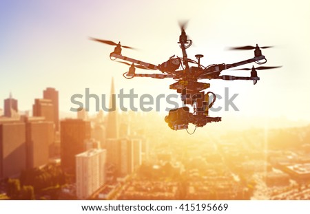 Innovation photography concept. Silhouette drone Flying over San-Francisco city on blurred background. Heavy lift drone photographing city at sunset.  Royalty-Free Stock Photo #415195669