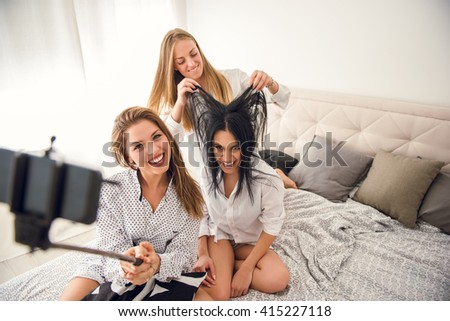 Girls making a crazy selfie with selfie stick.