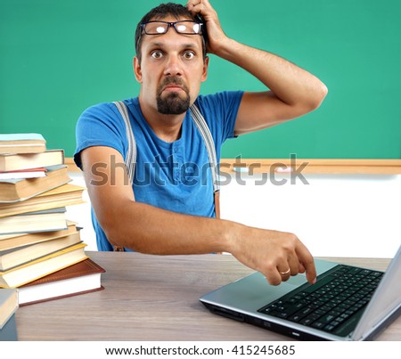 Teacher looking at camera with an expression of incomprehension face. Photo of man working at computer, education concept