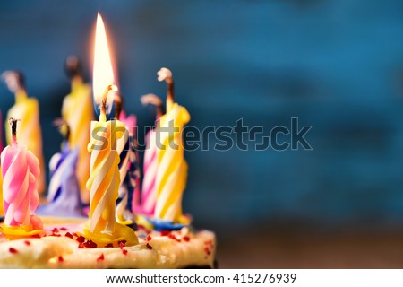 closeup of some unlit candles and just one lit candle after blowing out the cake Royalty-Free Stock Photo #415276939