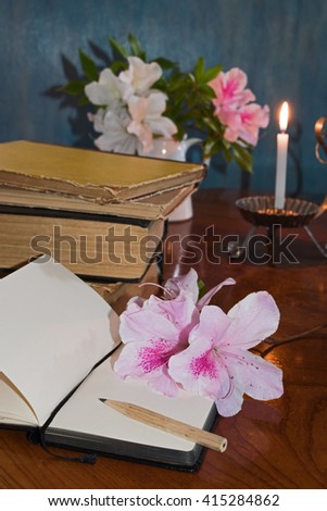 Stack of books on a wooden table with candle