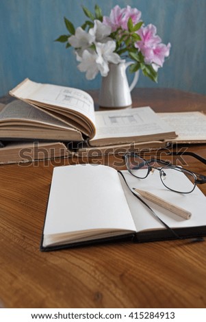 Stack of books on a wooden table with glasses