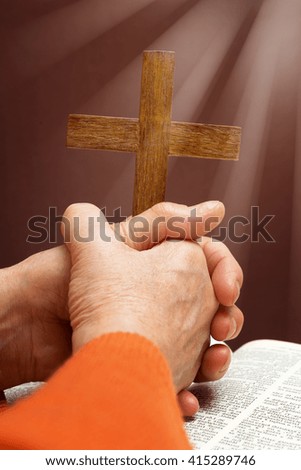 Male hands holding wooden cross on brown background