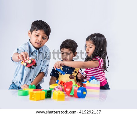 Cute little Indian/asian kids playing with toys or blocks and having fun while sitting at table or isolated over white background
