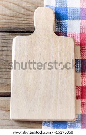 Empty cutting board on wooden table and kitchen rag. Concept for restaurant menu. Plenty of copy space