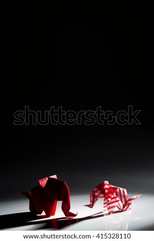 Beautiful back light scene of red origami elephants isolated on black background