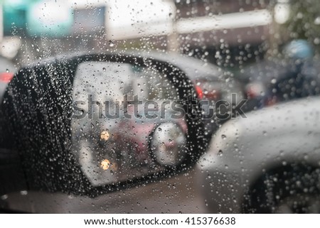 Car side mirror for rear view and rain water drops with traffic reflection background