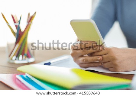 high school, education, people and learning concept - close up of young student or woman with smartphone and book writing to notebook at home Royalty-Free Stock Photo #415389643