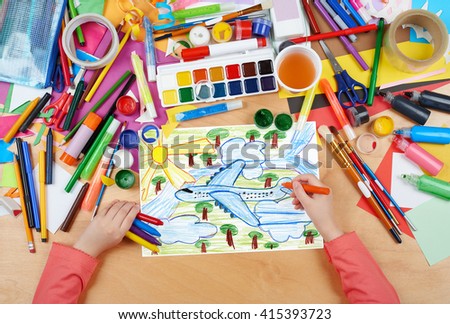 airliner fly high above the earth, child drawing, top view hands with pencil painting picture on paper, artwork workplace