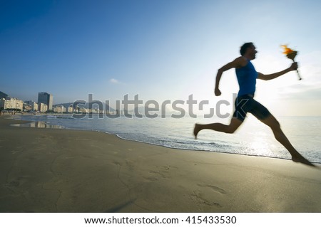 Motion blur silhouette of an athlete running with sport torch on Copacabana Beach in Rio de Janeiro, Brazil