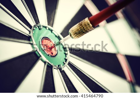 Dart arrow hitting in the target center of dartboard Royalty-Free Stock Photo #415464790
