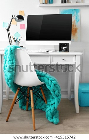 Modern wide screen monitor on white table and chair in room interior