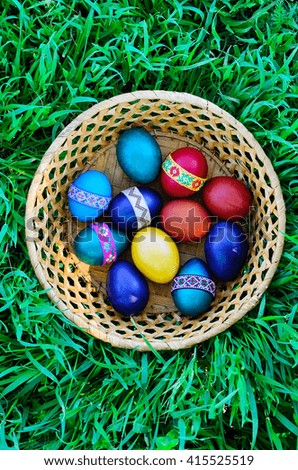 Easter eggs in the basket on the green grass. Top view