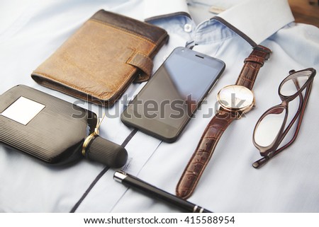 watches, glasses, wallet, perfume and phone on shirt