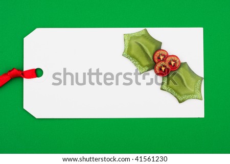 A blank gift tag with holly on a green background