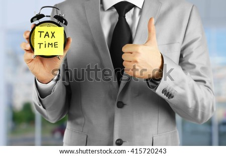 Tax concept. Businessman holding alarm clock, tax time
