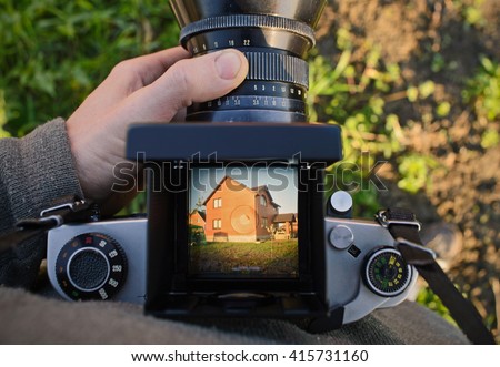 man photographer is making architecture photography with old film camera in spring,  home and building concept. top view. copy space
