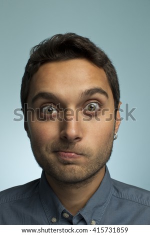 Portrait of a young man making funny face against blue backgroun