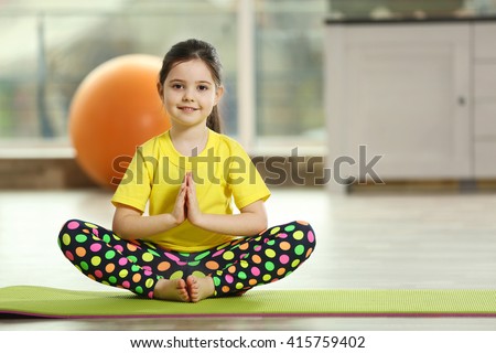 Little cute girl practicing yoga pose on a mat indoor Royalty-Free Stock Photo #415759402